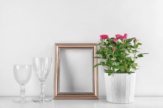 Vase with roses, wine glasses and photo frame on table