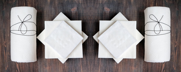 White paper tissue roll, paper napkins on rustic wooden background. Top view. Copy space. Wide panoramic.