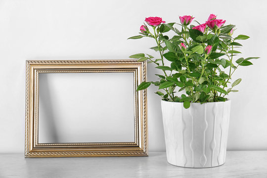 Vase with roses and photo frame on table