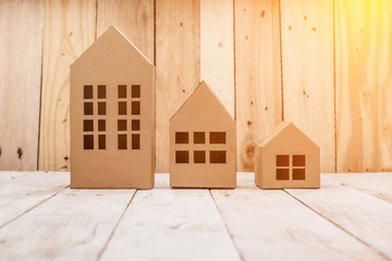 model of cardboard house on wooden floor and background