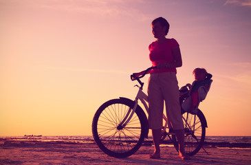Obraz premium Silhouette of mother and baby biking at sunset