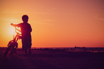 Fototapeta na wymiar little boy riding bike at sunset beach
