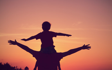 father and son having fun on sunset sky