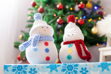 Two handmade snowmen with Christmas background on white fur