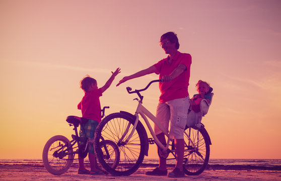 silhouette of father with two kids on bikes