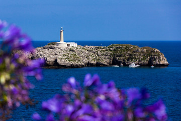 Lighthouse on the island with flowers on the foreground (Santander, Spain)