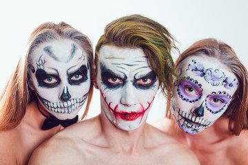 Two girls and a guy with Halloween face art on white background