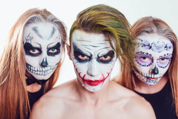 Two girls and a guy with Halloween face art on white background