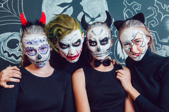 Three girls and a guy with Halloween face art on dark background pattern