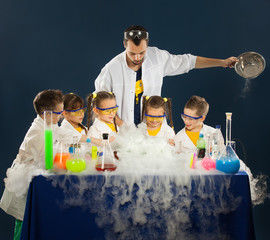 Happy kids with scientist doing science experiments in the laboratory