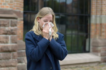 Sick young woman blowing her nose