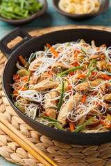 Rice noodles with chicken, mushrooms mun and vegetables in wook.