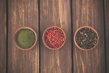 three small bowls of spice at wooden background, toned