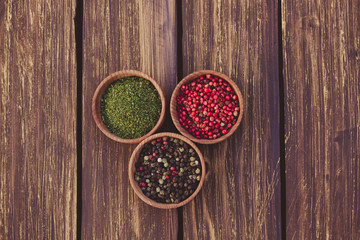 three small bowls of spice at wooden background