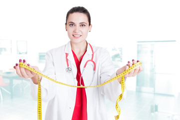 Young woman doctor holding measuring tape