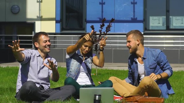 happy students sitting on the lawn and sing