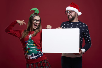 Pointing on placard in christmas clothes