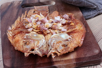Deep fried fish ,Nile tiapia, with crispy garlic on butcher served. Selective focus