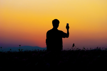 Silhouette of man posing at sunset sky background.