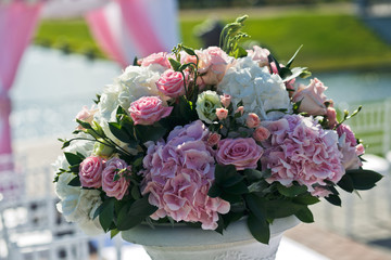 Rich bouquet made of white and pink flowers stands on the Greek