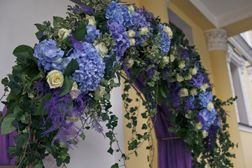 Greenery hangs from the rich wedding altar made of blue and viol