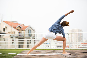 Beautiful woman doing yoga outdoors on a rooftop terrace