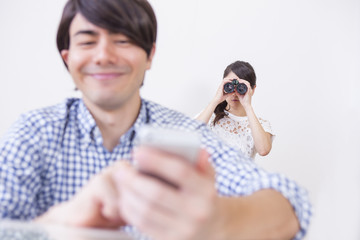 スマホをいじる男性と後ろから見る女性