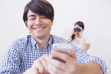 スマホをいじる男性と後ろから見る女性