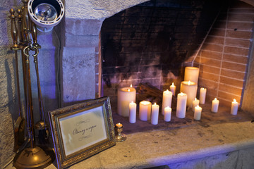 Sparkling white candles stand in old fireplace