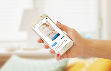 Fototapeta premium Online shopping with smart phone in woman hand. Web site or app on phone display. Room interior in background.