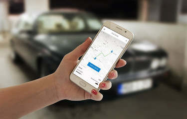 Hire taxi driver with smart phone app. Black car in background. Phone in woman hand.