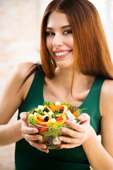 Beautiful young woman eating salad, indoor