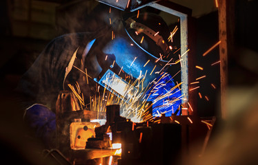 worker is welding automotive part in factory