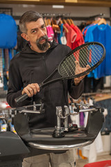 Stringing Machine. Tennis stringer doing racket stringing in his workshop