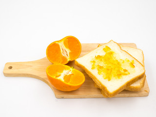 Fresh orange with orange jam and bread on wooden tray over white background.