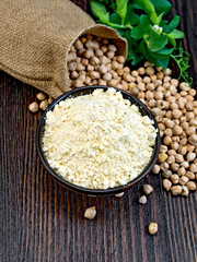 Flour chickpeas in bowl with peas on dark board