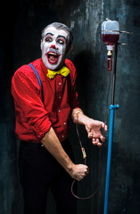 The scary clown and drip with blood on dack background. Halloween concept