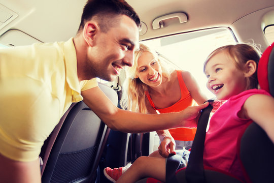 happy parents fastening child with car seat belt
