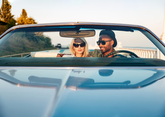 Beautiful young couple sitting and driving cabriolet