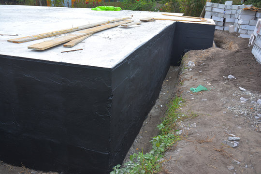 Close up on Waterproofing and insulation house foundation wall. Foundation  Waterproofing and Damp proofing Coatings. Waterproofing house foundation  with bitumen spray on tar Stock Photo