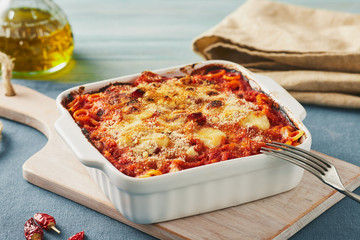 Baked anelletti pasta with mince, sauce and mozzarella. Typical sicilian dish - obrazy, fototapety, plakaty