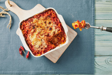 Baked anelletti pasta with mince, sauce and mozzarella. Typical sicilian dish