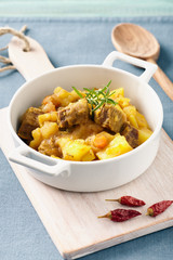 Sicilian stew in a white pot on a blue table, pastel color