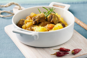 Sicilian stew in a white pot on a blue table, pastel color