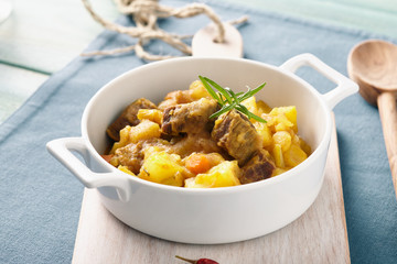Sicilian stew in a white pot on a blue table, pastel color