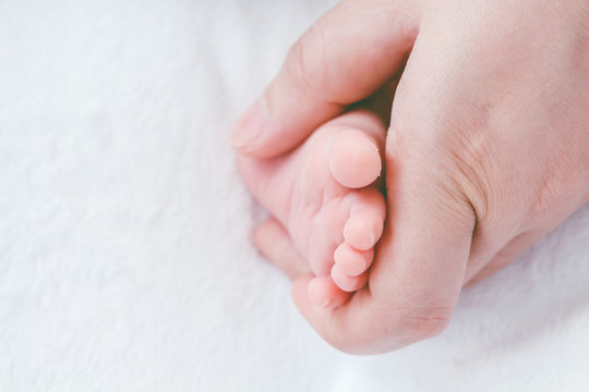 Newborn baby feet on mother hands