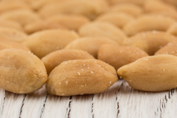 Salted peanuts on white old wooden table.