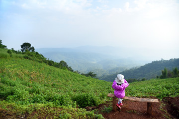 Naklejka na ściany i meble Young Asian girl sitting on a chair with mountain view in Maerim, Mon Jam, Chiangmai, north of Thailand