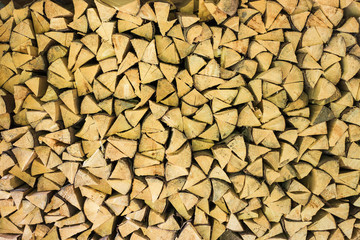 Many dry chopped firewood in storage ready for use in cold winter season. Brown color wood background. Horizontal color image.