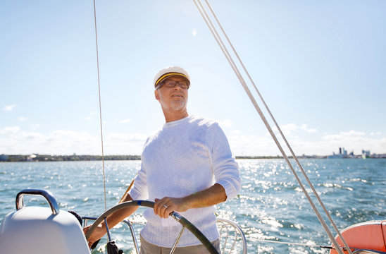 senior man at helm on boat or yacht sailing in sea